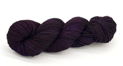 A skein of yarn shaded in dark velvety purple and plum tones.
