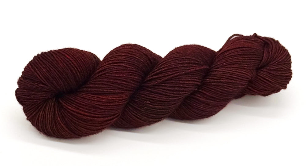 A skein of yarn in rich mahogany and deep red-black hues.