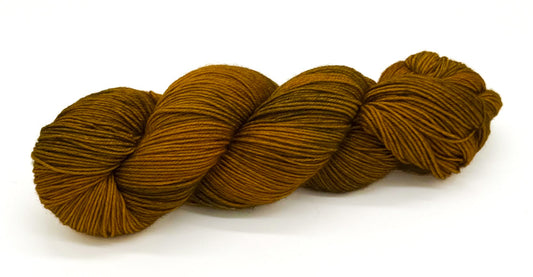 A skein of yarn glowing with golden ochre and soft olive tones.