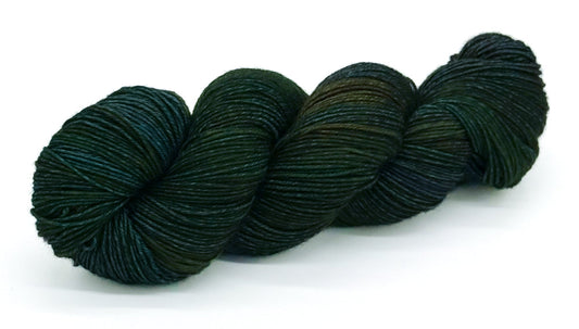 A skein of yarn in a medley of forest greens and moss hues.