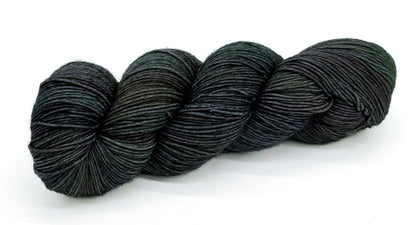 A skein of yarn with dark rustic greens and deep river blues.