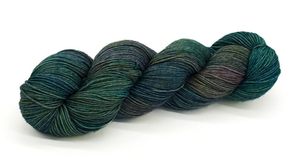 A skein of yarn in warm olives, gentle browns and mossy greens.