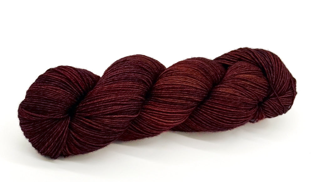 A skein of yarn swirled with deep wine, maroon and shadowed plum.