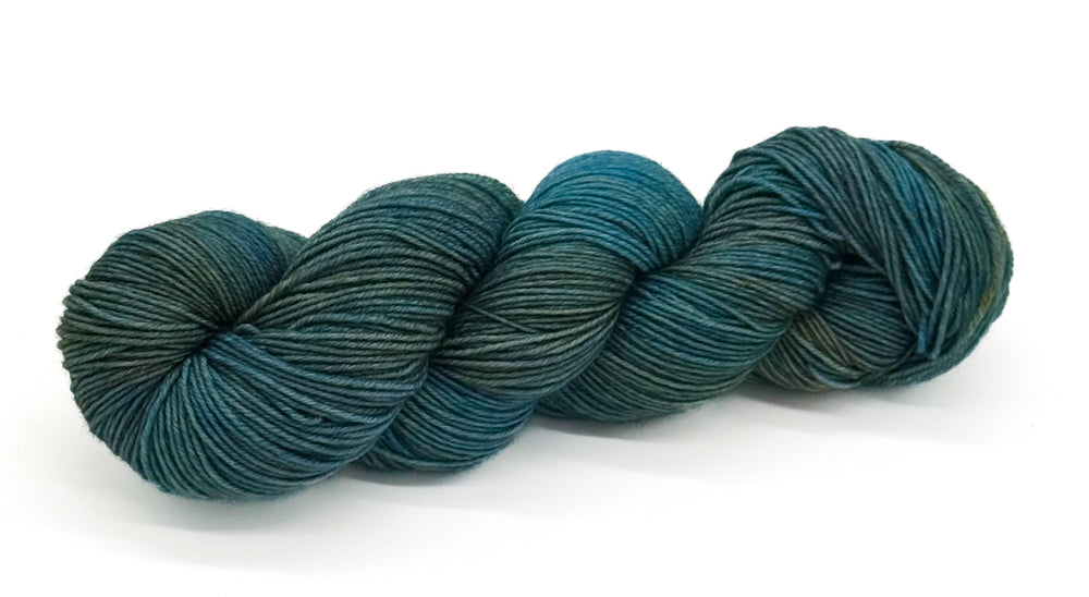 A skein of yarn with seafoam teal, ocean mist and dusky tidepool greens.