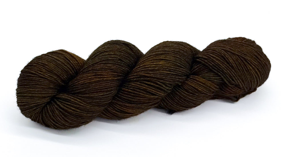 A skein of yarn blending deep olive, bark and forest-shadow greens.