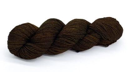 A skein of yarn blending deep olive, bark and forest-shadow greens.