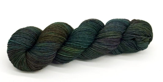 A skein of yarn with vibrant emerald, moss and woodland greens.