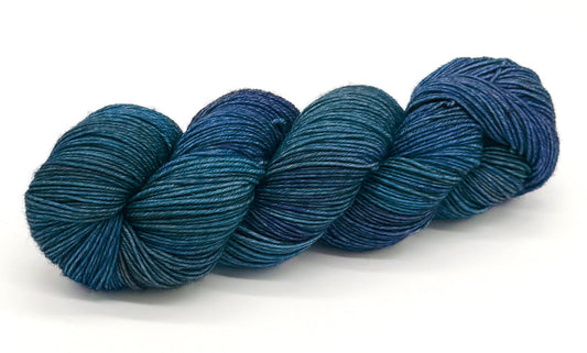 A skein of yarn in shimmering ocean blues and coastal hues.