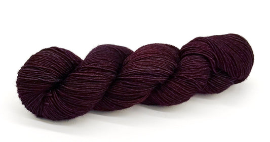A skein of yarn in rich merlot and velvety plum tones.