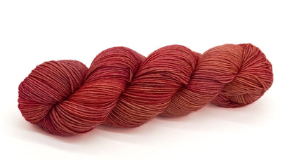 A skein of yarn blending strawberry, peach and soft terracotta hues.