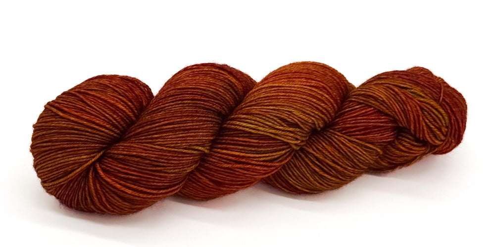 A skein of yarn in rustic maple, burnt orange and cedar tones.