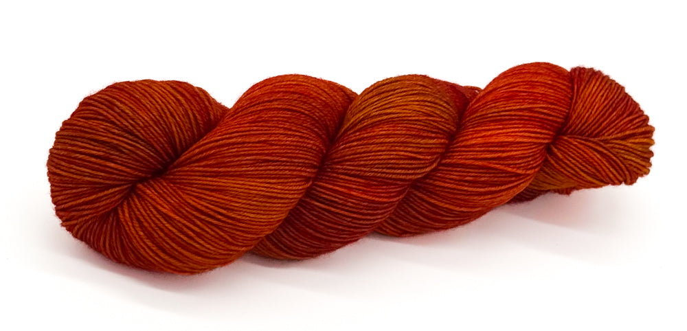 A skein of yarn with vibrant alpine reds, spicy cinnamon and golden undertones.