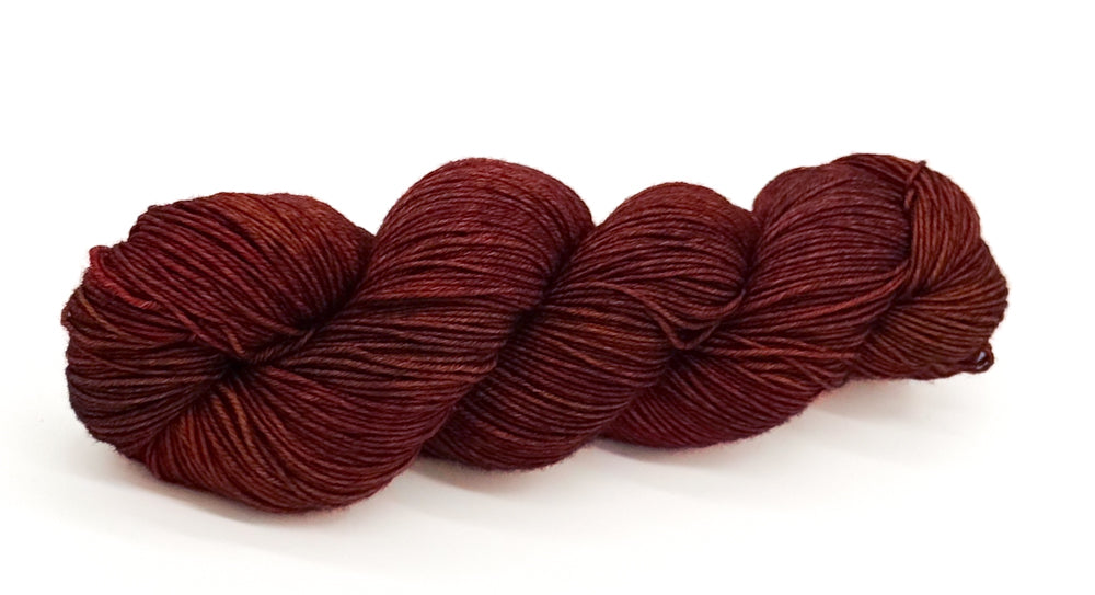 A skein of yarn swirling warm wine-reds and earthy mahogany hues.