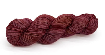 A skein of yarn shaded in soft mauve, dusty rose and aged parchment tones.